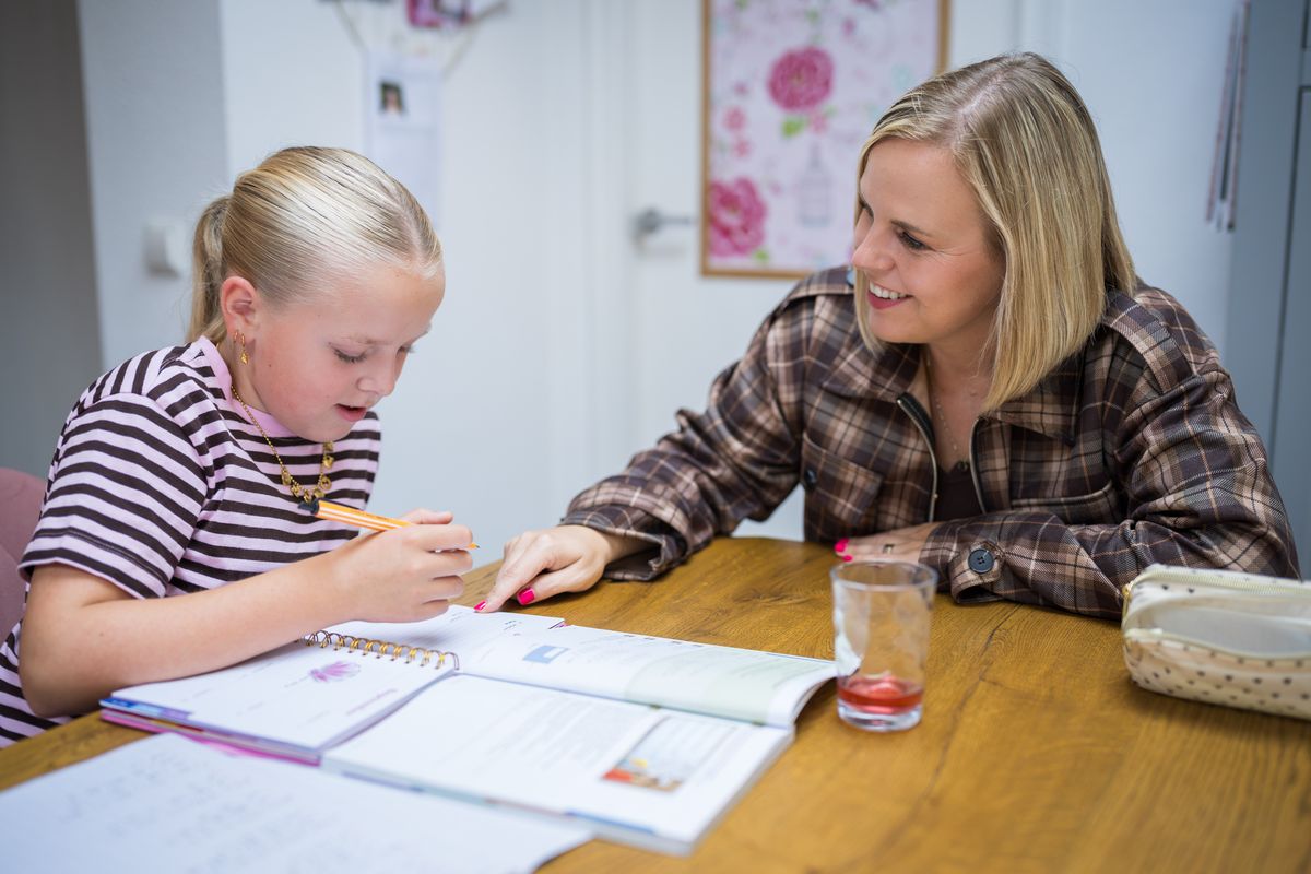 Suzanne kijkt mee terwijl een leerling aan tafel schrijft